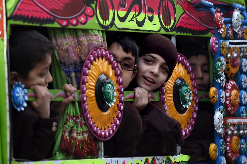 Pakistani children travel to school in a van in Peshawar