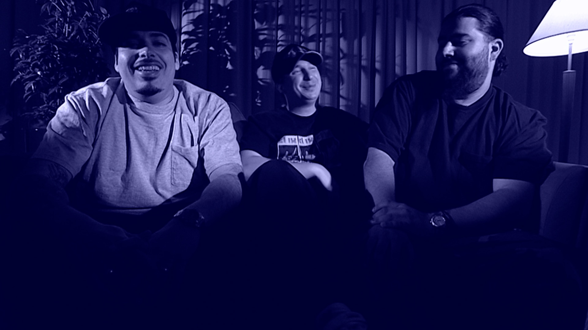 Deftones sitting on couch with a dark blue filter over the image