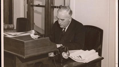 Former prime minister Robert Menzies sitting at his desk.
