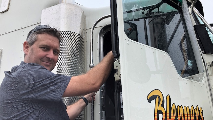 Man climbs into the open door of the cab of a truck