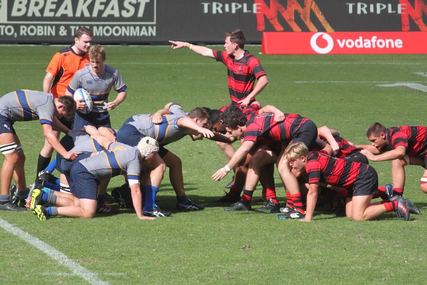 Two teams of teenage boys set a scrum