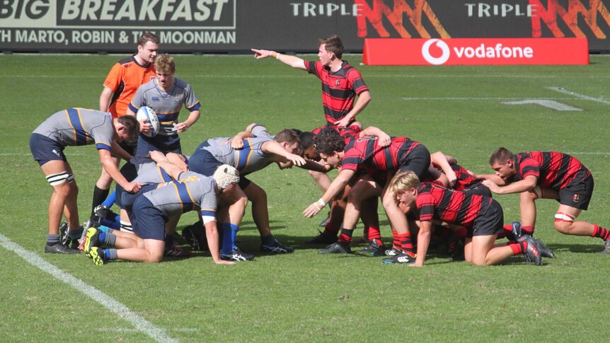 Two teams of teenage boys set a scrum