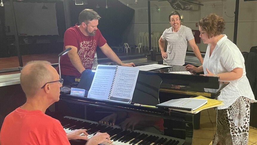 People stand around a grand piano