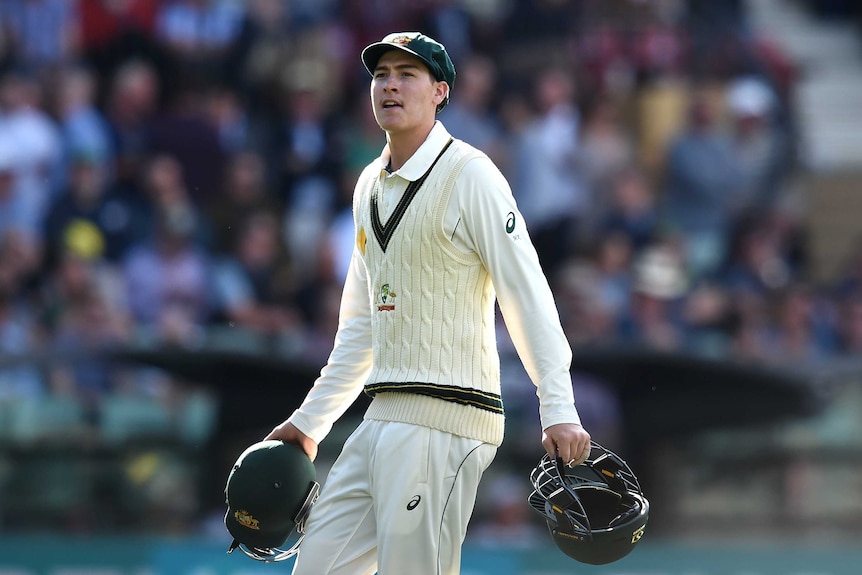 Matthew Renshaw holds two helmets on the cricket field