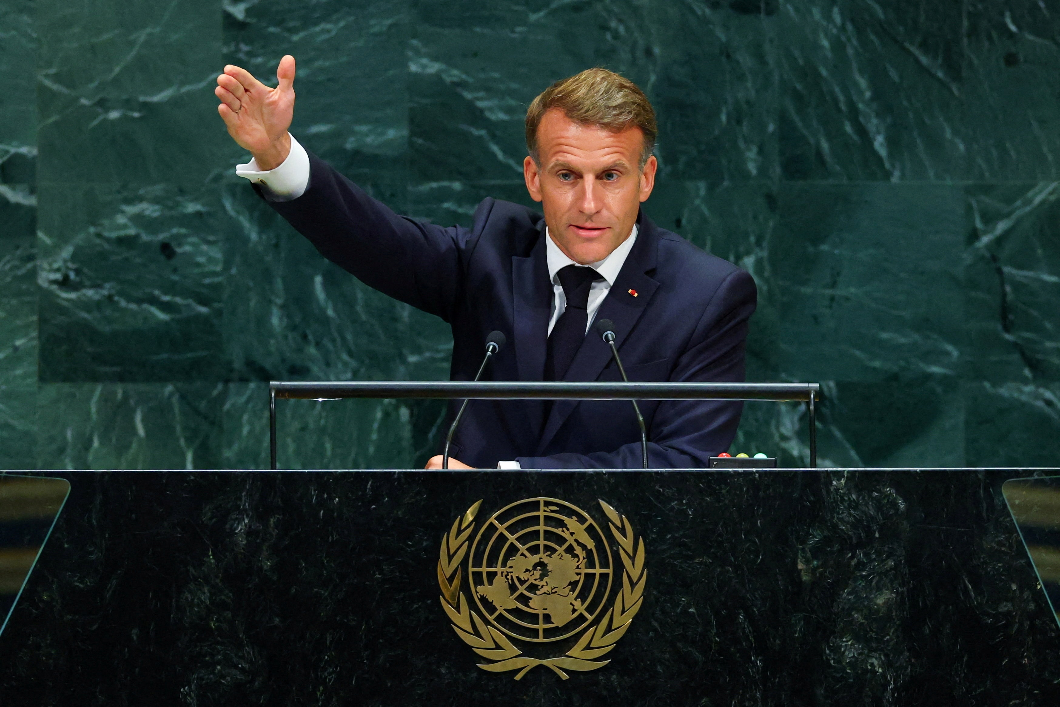 Macron speaks at a podium with one arm raised