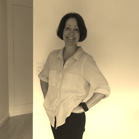 A woman smiles and poses for a photo that has been overlayed with a sepia filter, adjusting the colour to give it a yellow tone