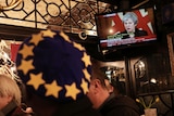 People in a pub watch Theresa May on television