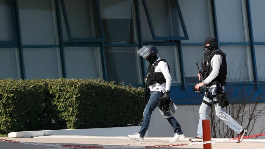 Armed police walk inside the high school grounds.