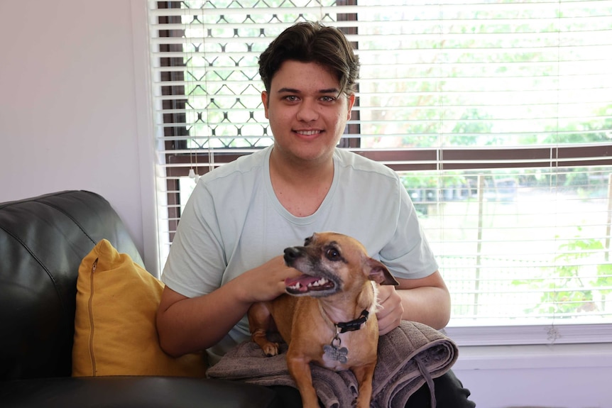A man sitting smiling with a dog on his lap.