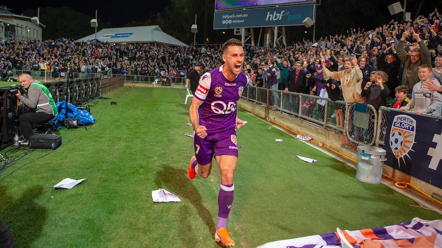 A football player runs to celebrate among fans after hitting the winning kick in a penalty shoot-out