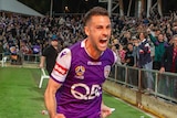 A football player runs to celebrate among fans after hitting the winning kick in a penalty shoot-out