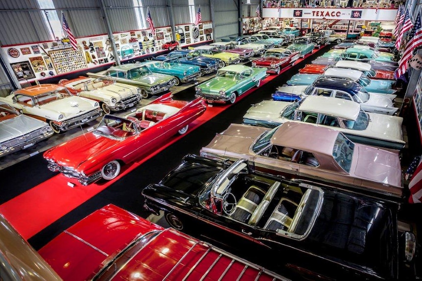 Looking down on rows of 1950s and 1960s classic American cars in a big shed.