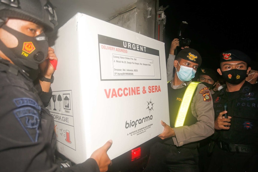 Two men wearing masks, helments and police uniforms hold a box marked Urgent Vaccine and Sera