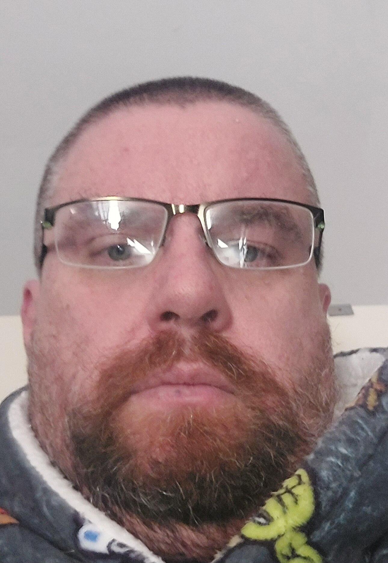 A middle-aged man wearing glasses looks directly into camera