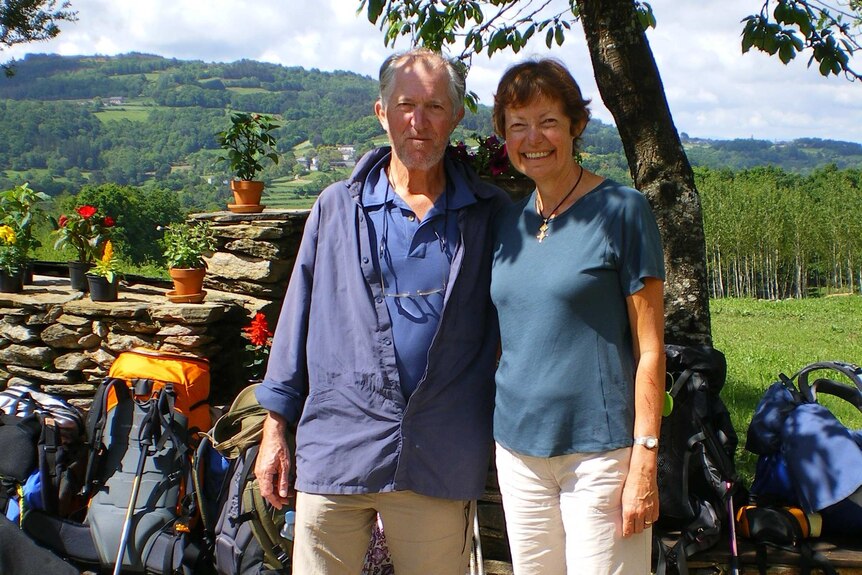 Clive Deverall and Noreen Fynn smile in front of hiking poles and backpacks.
