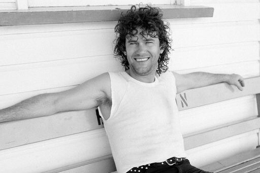 Jimmy Barnes sitting on a park bench with his arms outstretched