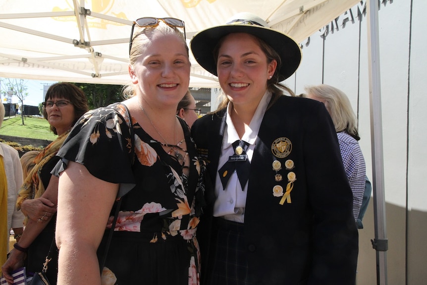 Two girls stand side by side and smile at the camera.