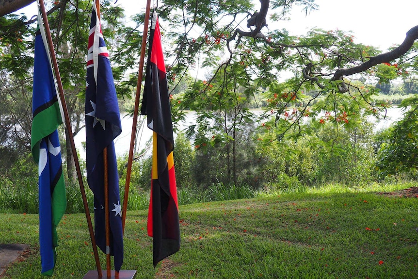 The Aboriginal and Torres Strait Islander flags on poles next to the Brisbane river for the ceremony.