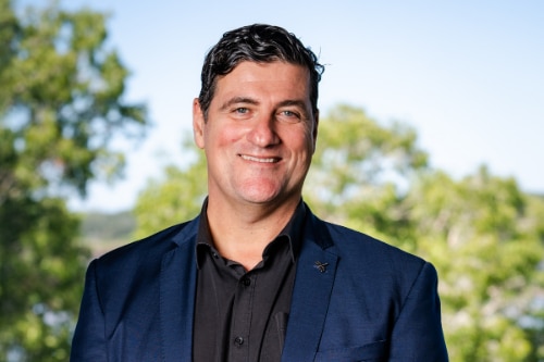 A man in a suit smiles for a professional portrait.