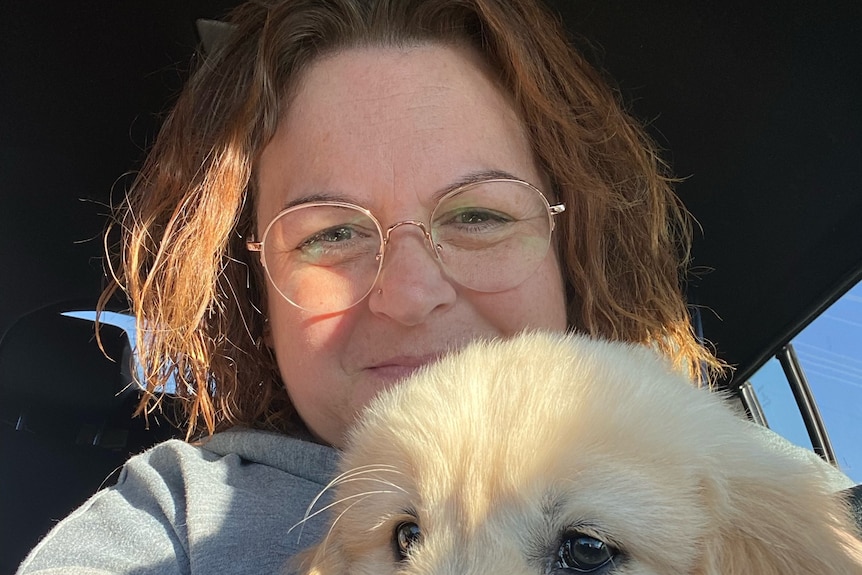 A woman holds a fluffy dog.