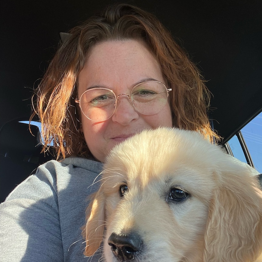 A woman holds a fluffy dog.