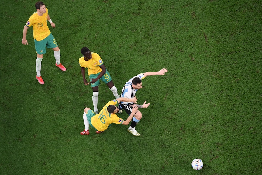 Seen from above, three Socceroos try to tackle Argentina's Lionel Messi but the ball is already gone at the Qatar World Cup.
