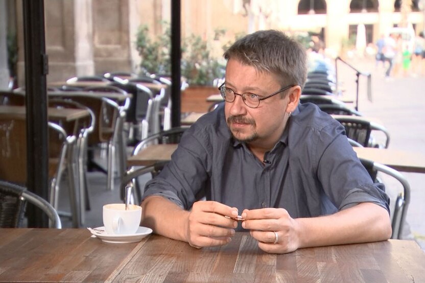 Congressman Xavi Domenech sits in a cafe with a coffee.