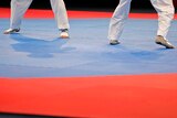 An image of the feet of two athletes competing on the mat in a taekwondo tournament