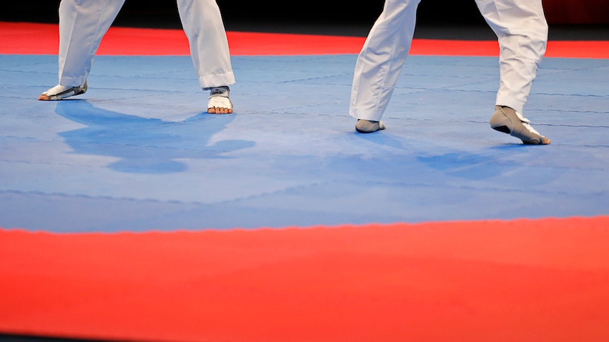An image of the feet of two athletes competing on the mat in a taekwondo tournament