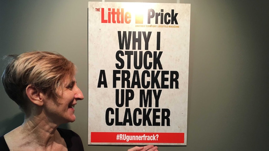 Artist Therese Ritchie stands looking at a poster.