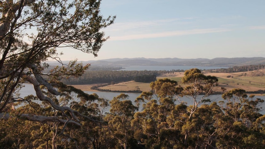 Landscape, looking from a mountain-top, over trees and down to a river running through a valley