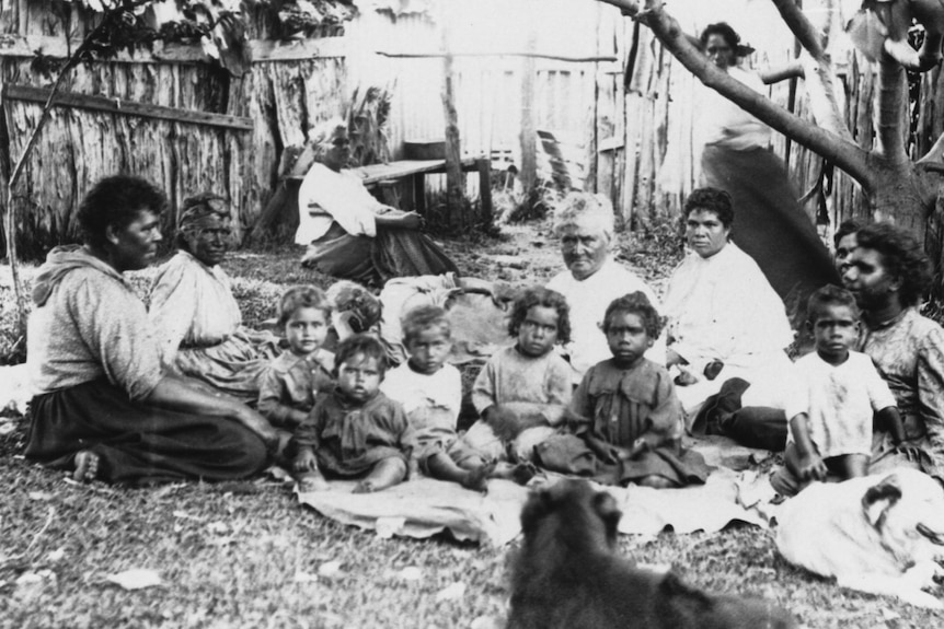 Women and children sit on grass in archival image