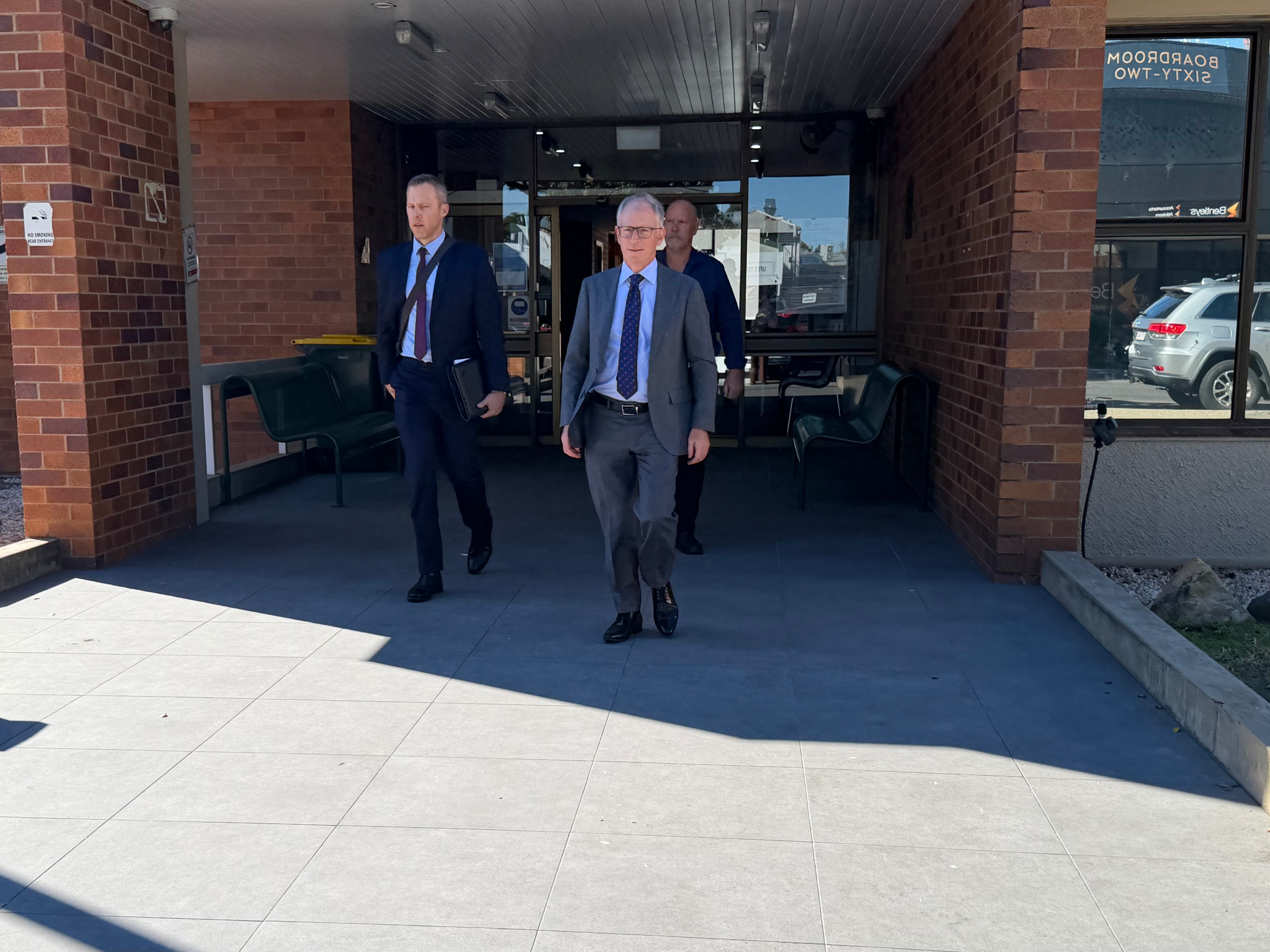 Three men in suits leaving courthouse building 