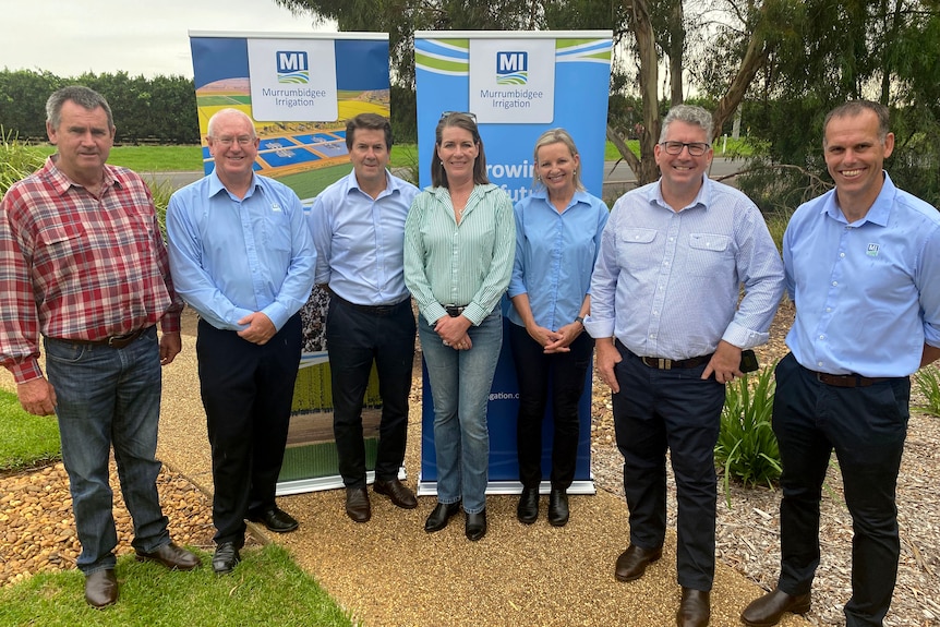 A group of seven people stand in front of Murrumbidgee Irrigation banners. 