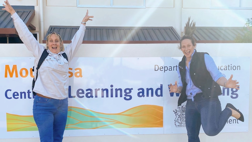 two women jumping in front of a business 