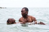 Mahershala Ali holds Alex R Hibbert in the water as he teaches the child to swim in a scene from Moonlight.