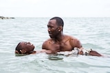 Mahershala Ali holds Alex R Hibbert in the water as he teaches the child to swim in a scene from Moonlight.