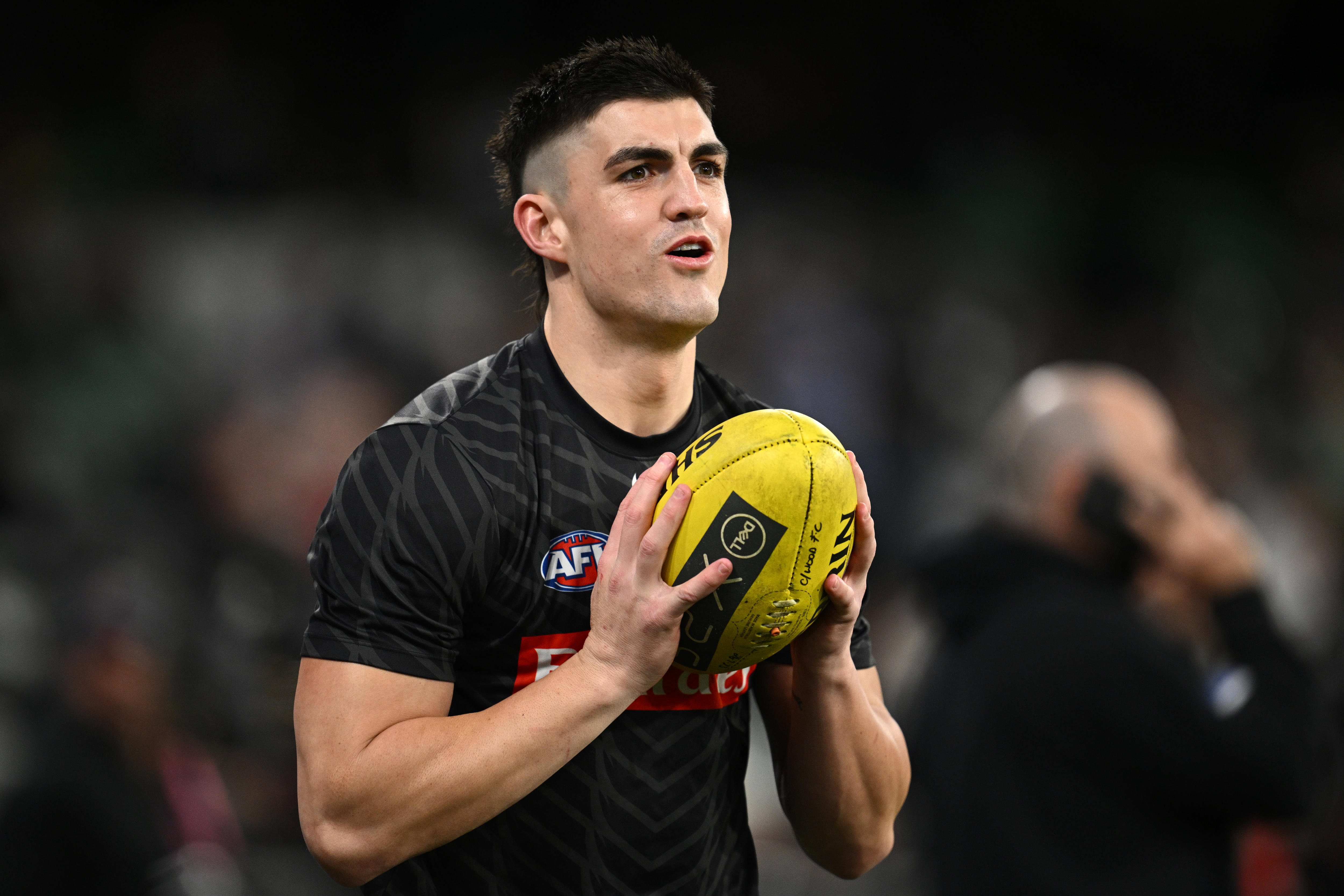An AFL player in a black training shirt, catches a football