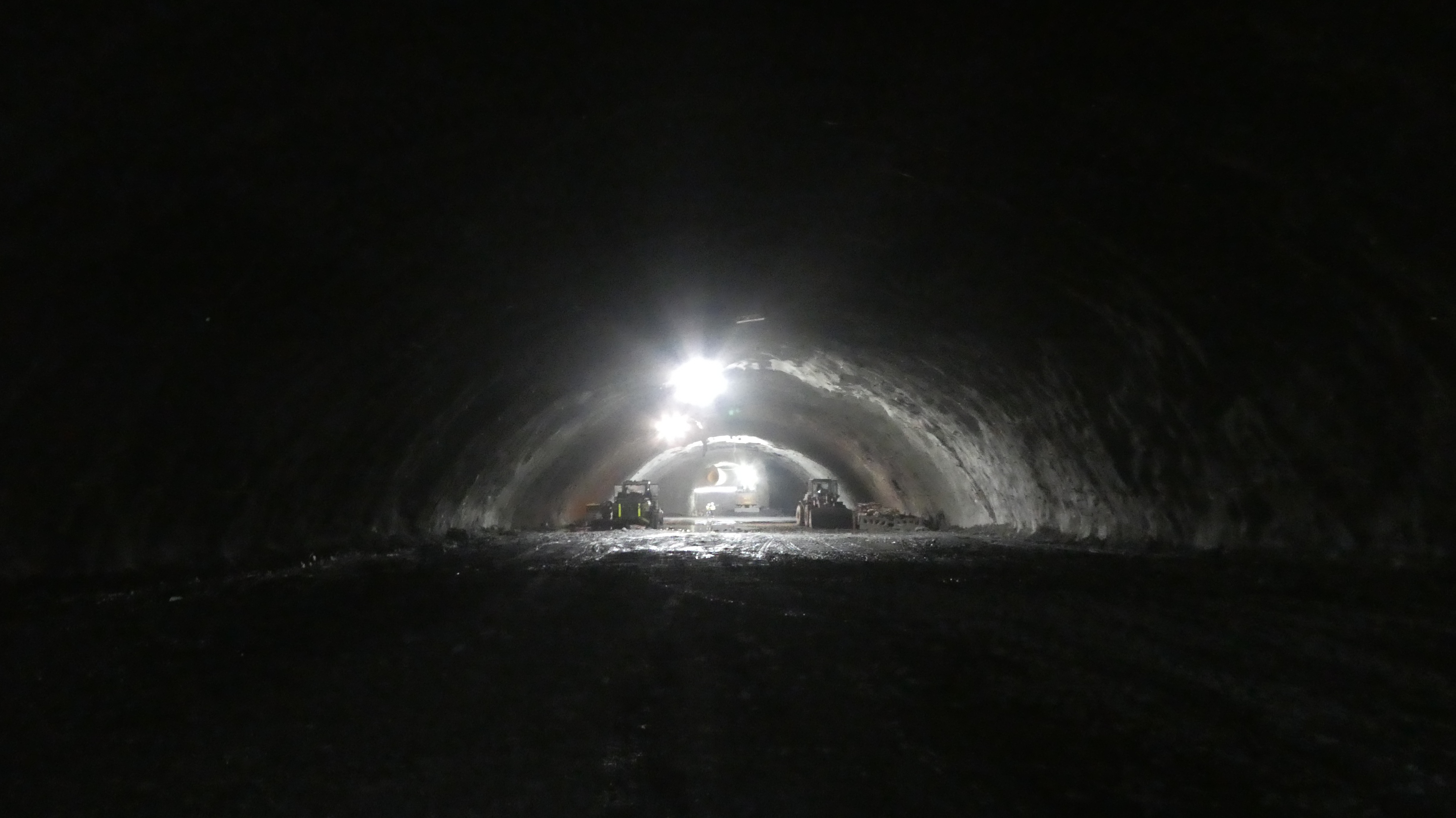 Construction machines in a shallow tunnel with an arched roof.