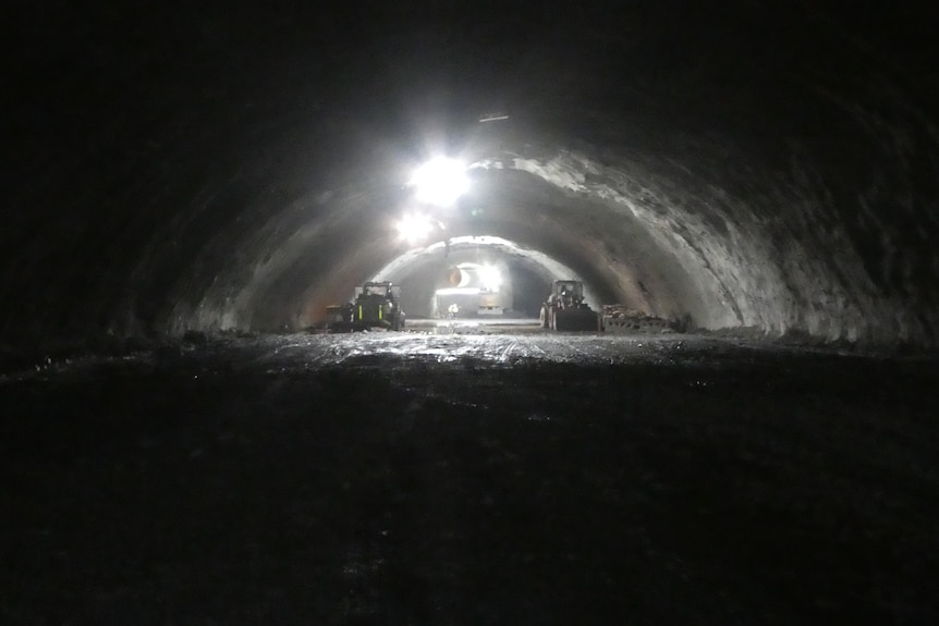 Construction machines in a shallow tunnel with an arched roof.