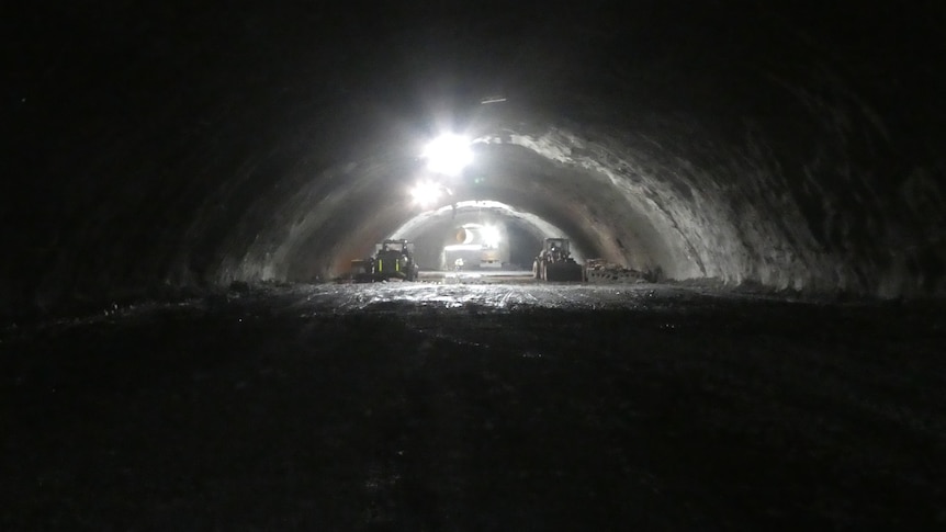 Construction machines in a shallow tunnel with an arched roof.