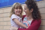 A mum holding her daughter on her hip 