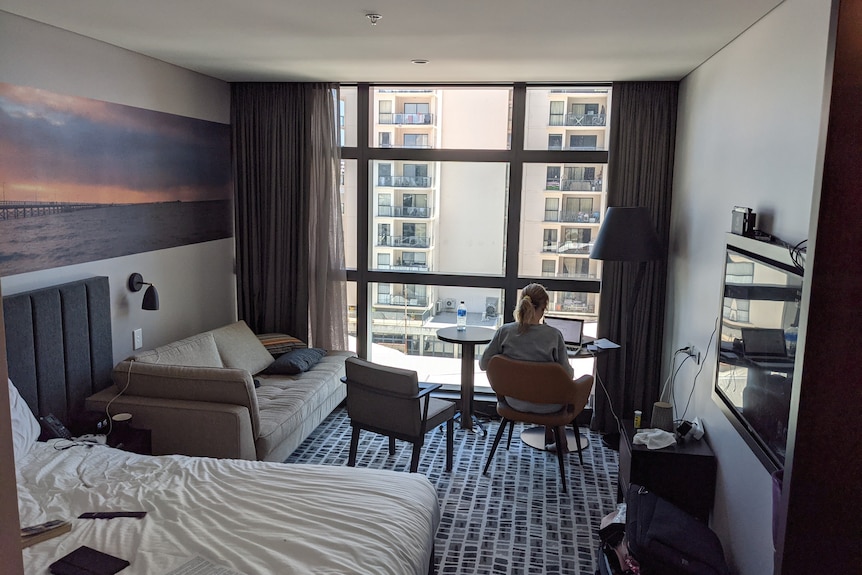 A woman looks out of a hotel window