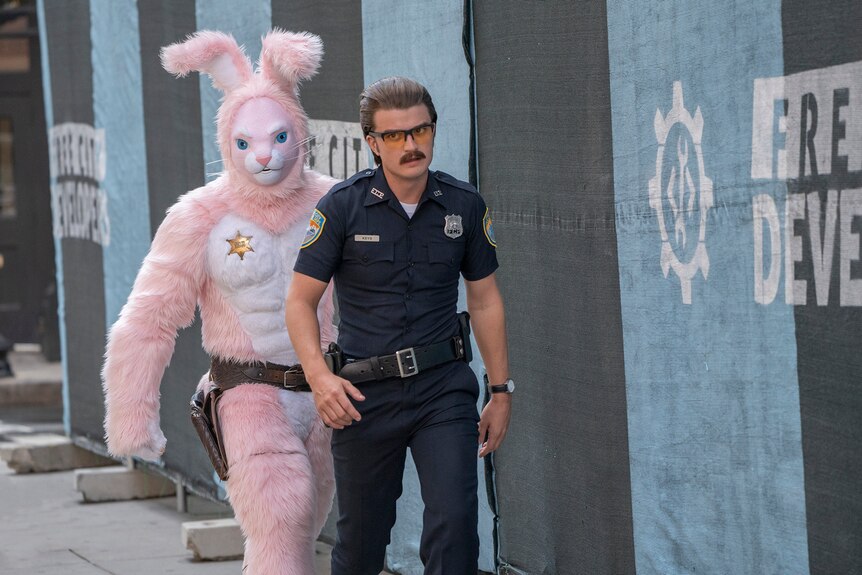 Film still from Free Guy (2021) featuring Utkarsh Ambudkar in a pink bunny suit and Joe Keery dressed as a police officer.