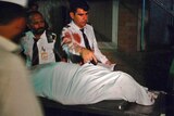 Crew members of the plane stand next to the body of a woman as it is removed from an ambulance.