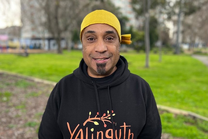 Jason Tamiru smiles, wearing a black hoodie and yellow beanie.