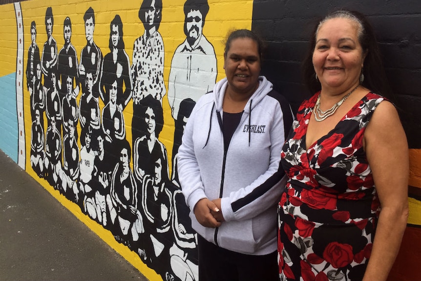 Margaret Miles and Donna Ingram stand in front of the Redfern mural.