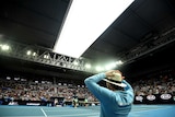 A linesman stands at courtside duri9ng a tennis tournament as the stadium roof begins to close.