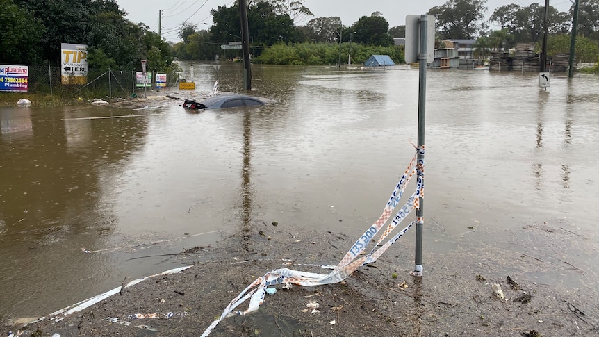 A car is almost completely submerged by flood water on a street in Camden