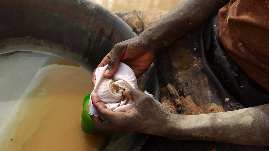 A mine worker holds flecks of gold